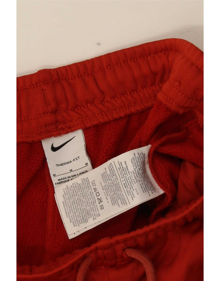 Męskie spodnie dresowe Nike Therma-Fit Graphic, poliestrowe, w kolorze średniej czerwieni